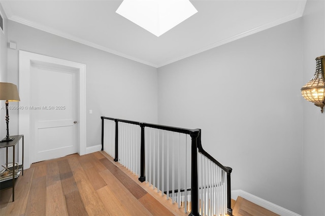 hallway featuring a skylight, light hardwood / wood-style flooring, and ornamental molding