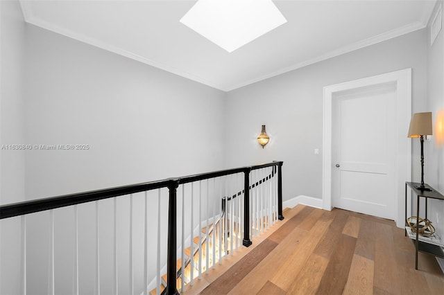 hall with a skylight, crown molding, and light wood-type flooring