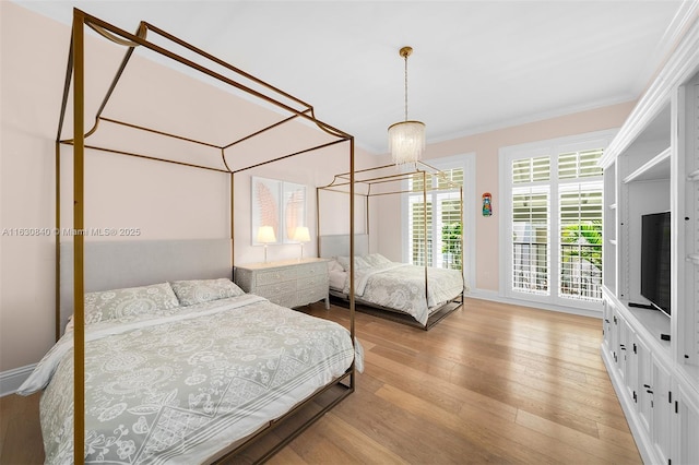 bedroom featuring crown molding, light hardwood / wood-style floors, and a notable chandelier