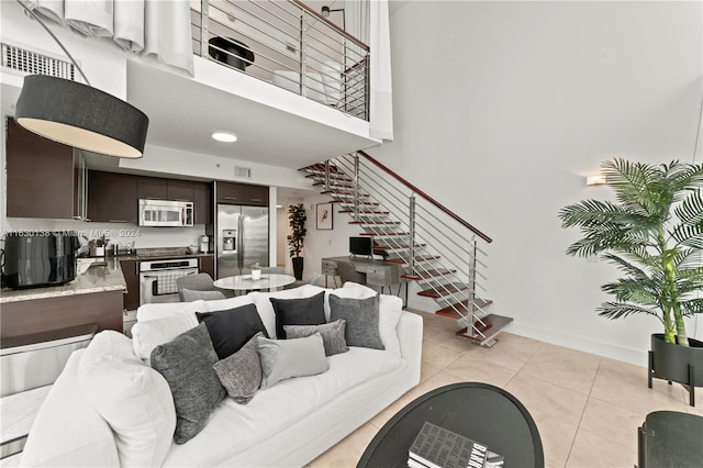 living room with a towering ceiling and light tile patterned flooring