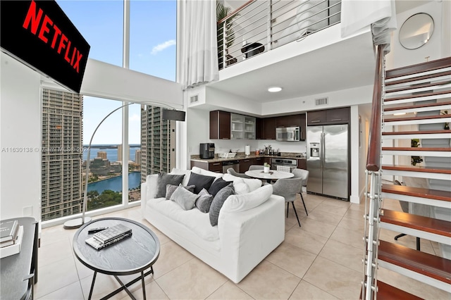 tiled living room featuring a water view and a high ceiling