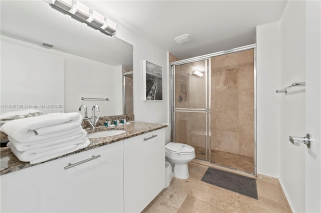 bathroom featuring a shower with shower door, toilet, and vanity