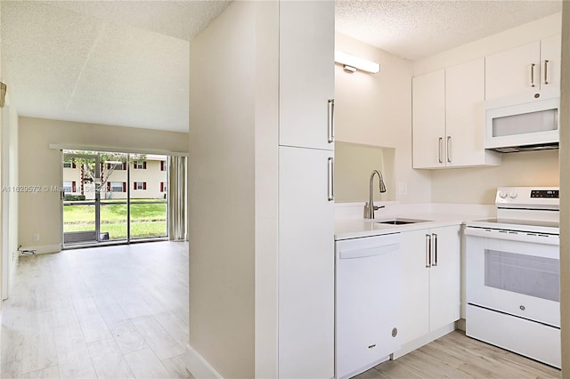 kitchen featuring a textured ceiling, white appliances, light wood-type flooring, sink, and white cabinetry