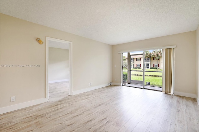 spare room with a textured ceiling and light hardwood / wood-style floors