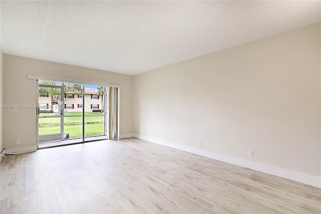 empty room featuring light wood-type flooring and a textured ceiling