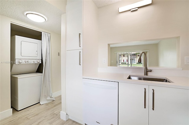 interior space with a textured ceiling, stacked washer and dryer, sink, and light hardwood / wood-style floors