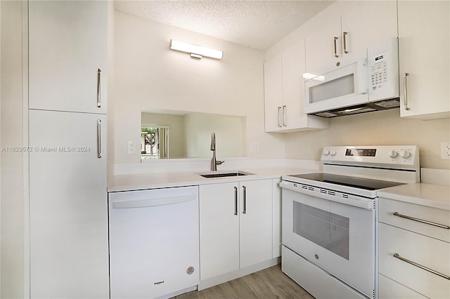 kitchen with a textured ceiling, white appliances, white cabinets, light wood-type flooring, and sink