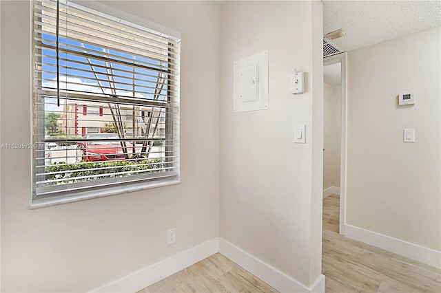 interior space featuring light hardwood / wood-style flooring, a textured ceiling, and electric panel