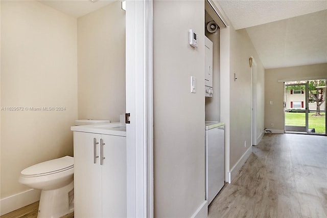 bathroom with a textured ceiling, toilet, vaulted ceiling, hardwood / wood-style flooring, and vanity