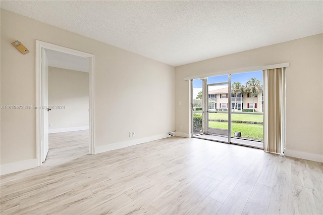 spare room featuring light hardwood / wood-style flooring and a textured ceiling