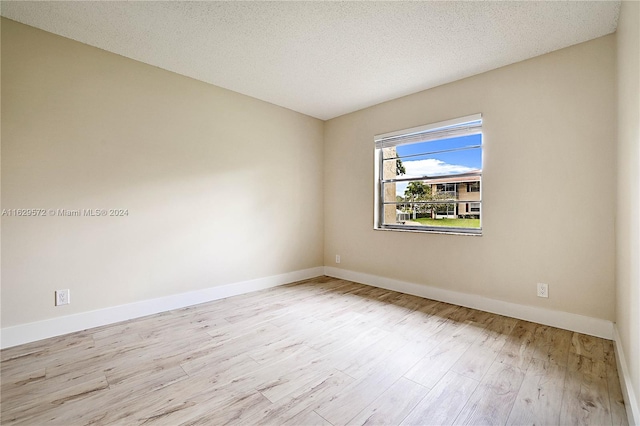 unfurnished room with light hardwood / wood-style flooring and a textured ceiling