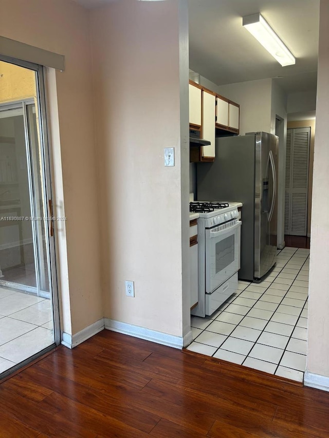 kitchen with extractor fan, white gas range, white cabinets, and light wood-type flooring