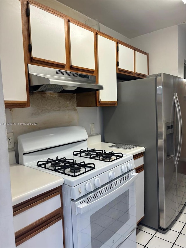 kitchen featuring white cabinetry, stainless steel fridge with ice dispenser, light tile patterned floors, white range with gas cooktop, and decorative backsplash