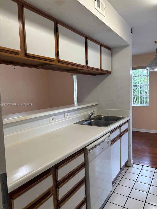 kitchen with decorative light fixtures, dishwasher, sink, white cabinets, and light tile patterned floors