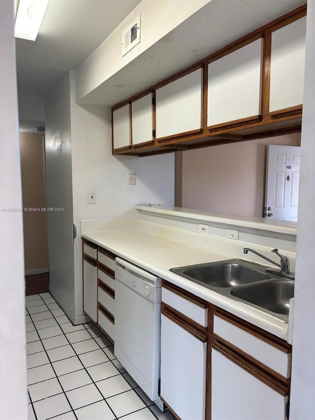 kitchen featuring dishwasher, sink, light tile patterned floors, and white cabinets