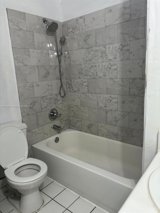 full bathroom with tile patterned floors, toilet, tiled shower / bath combo, and sink