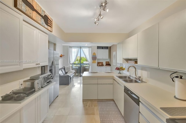 kitchen featuring white cabinets, track lighting, stainless steel dishwasher, light tile patterned floors, and sink