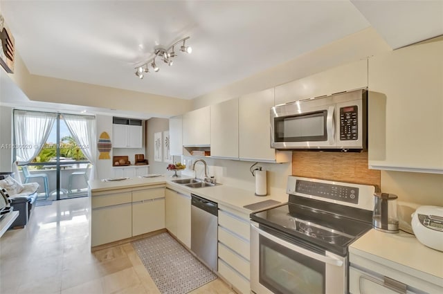 kitchen featuring rail lighting, light tile patterned floors, backsplash, stainless steel appliances, and sink