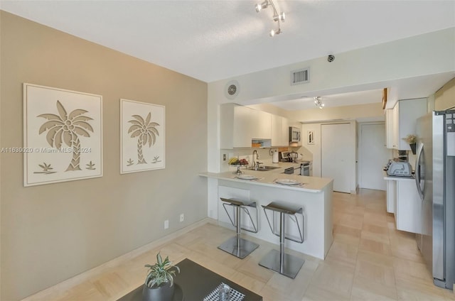 kitchen with appliances with stainless steel finishes, a kitchen breakfast bar, sink, light tile patterned flooring, and kitchen peninsula