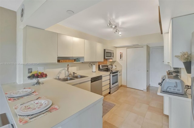 kitchen featuring appliances with stainless steel finishes, sink, white cabinets, light tile patterned floors, and track lighting