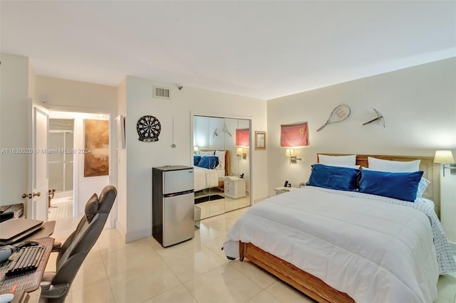 bedroom featuring light tile patterned floors, stainless steel refrigerator, and a closet