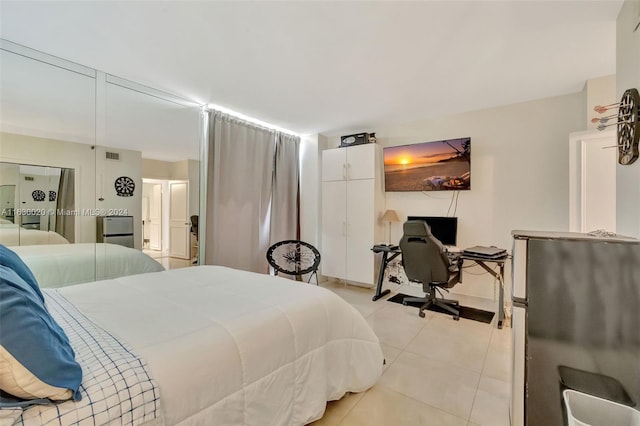 bedroom with stainless steel refrigerator and light tile patterned floors