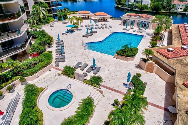 view of swimming pool with a patio, a hot tub, and a water view