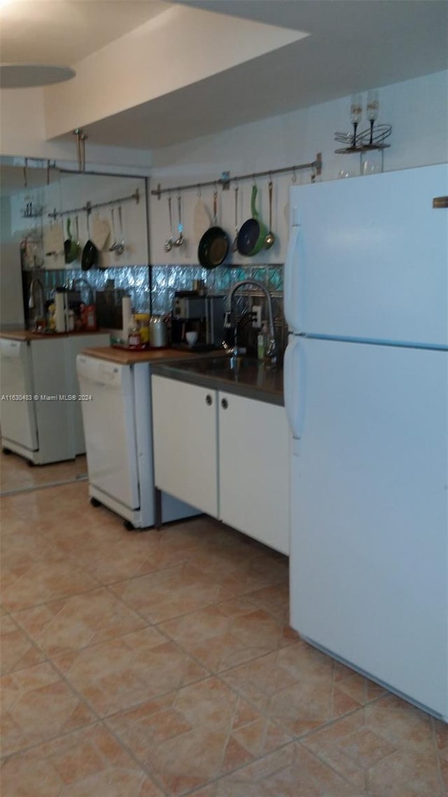 kitchen featuring sink, white appliances, light tile patterned floors, and white cabinets