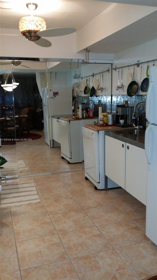 kitchen with light tile patterned flooring, white cabinetry, white appliances, and sink