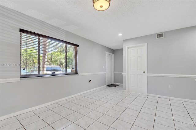 spare room with a textured ceiling and light tile patterned floors