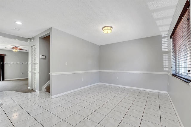 tiled spare room with a textured ceiling and ceiling fan