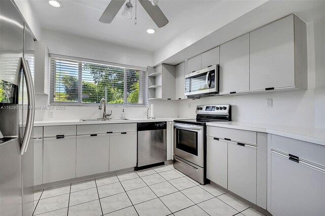 kitchen with stainless steel appliances, sink, light tile patterned flooring, white cabinetry, and ceiling fan