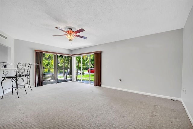 carpeted spare room featuring a textured ceiling and ceiling fan