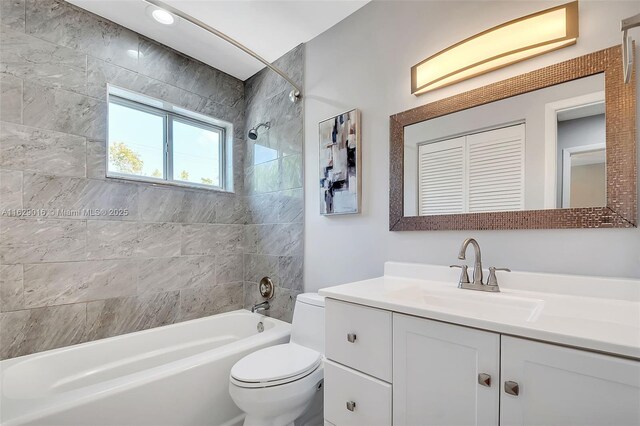 full bathroom with tiled shower / bath combo, vanity, and toilet