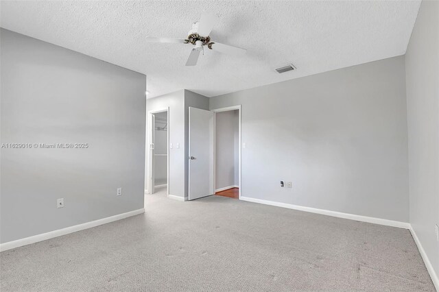 spare room with a textured ceiling, carpet floors, and ceiling fan