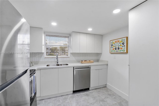 kitchen with appliances with stainless steel finishes, sink, white cabinets, and backsplash