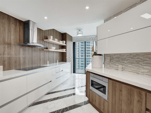 kitchen featuring white cabinetry, light tile patterned flooring, decorative backsplash, and wall chimney exhaust hood