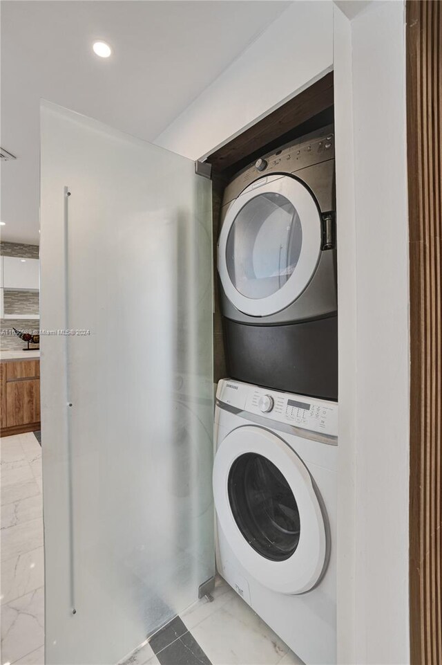 laundry room featuring stacked washer and dryer and light tile patterned floors