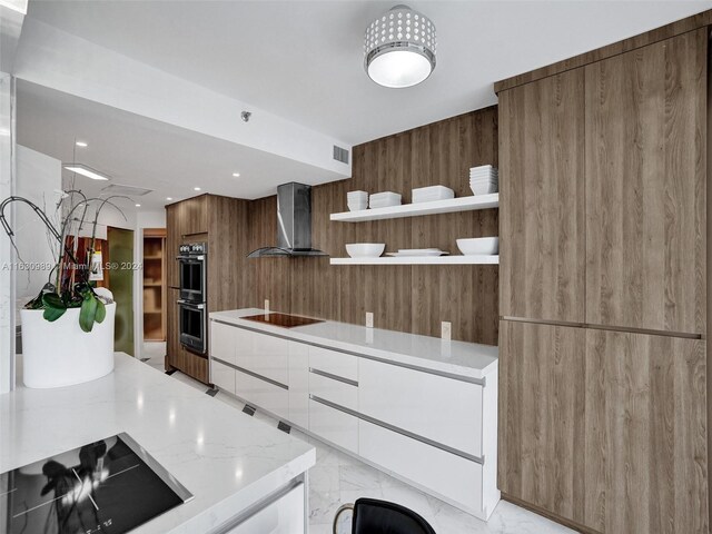 kitchen with light tile patterned floors, light stone countertops, black electric cooktop, stainless steel double oven, and wall chimney exhaust hood