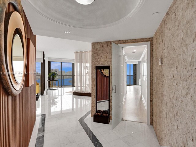 hallway with light tile patterned floors and a tray ceiling