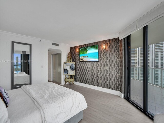 bedroom with wood-type flooring, multiple windows, and access to exterior