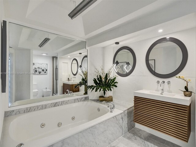 bathroom featuring a relaxing tiled tub, vanity, tile patterned flooring, and toilet