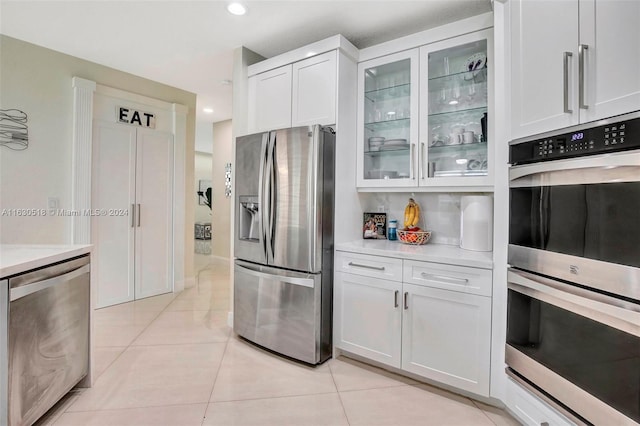 kitchen featuring appliances with stainless steel finishes, light tile patterned floors, and white cabinets