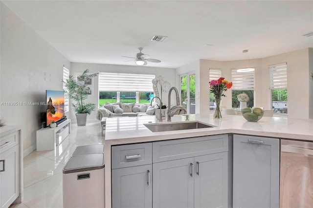 kitchen featuring decorative light fixtures, dishwasher, sink, gray cabinetry, and ceiling fan