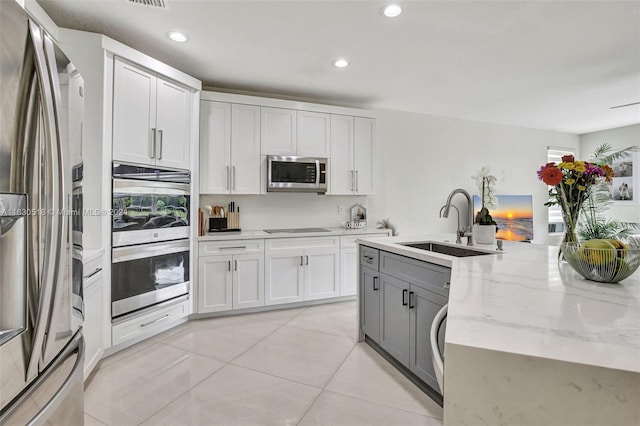 kitchen featuring white cabinets, stainless steel appliances, light stone countertops, and light tile patterned floors