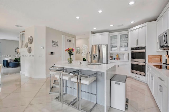 kitchen with white cabinets, a kitchen breakfast bar, stainless steel appliances, and light tile patterned floors