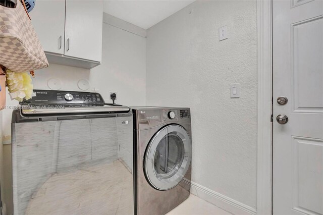 laundry room with light tile patterned flooring, washing machine and dryer, and cabinets