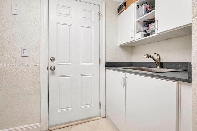 bar with white cabinetry, sink, and light tile patterned floors