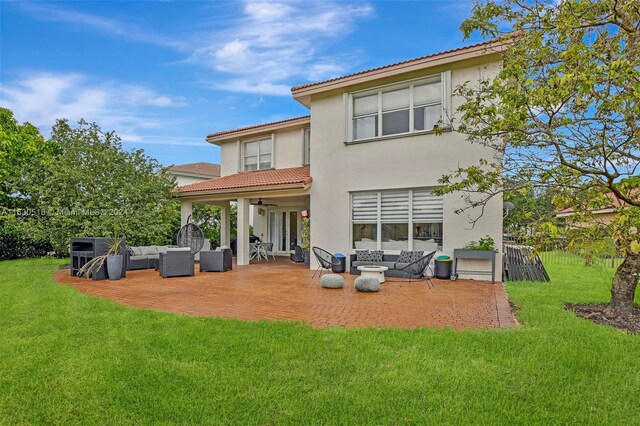 rear view of property featuring outdoor lounge area, a patio, and a lawn