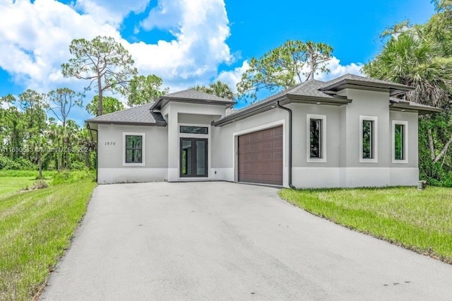 prairie-style house featuring an attached garage, stucco siding, and a front yard